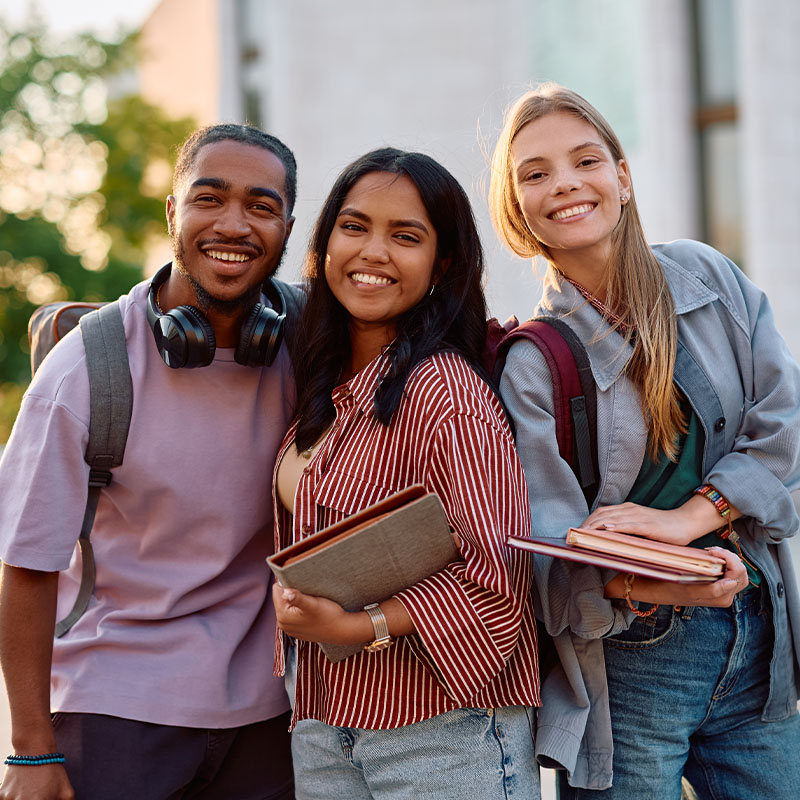 Group of happy students at university campus looking at camera.