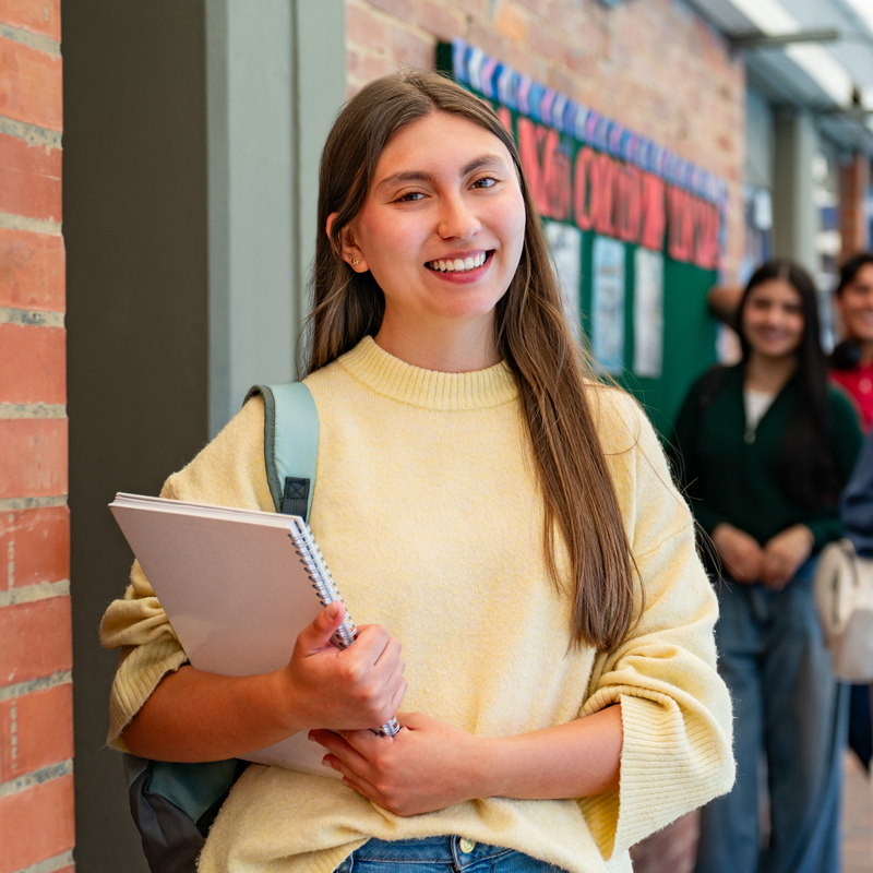 student holding a book smiling